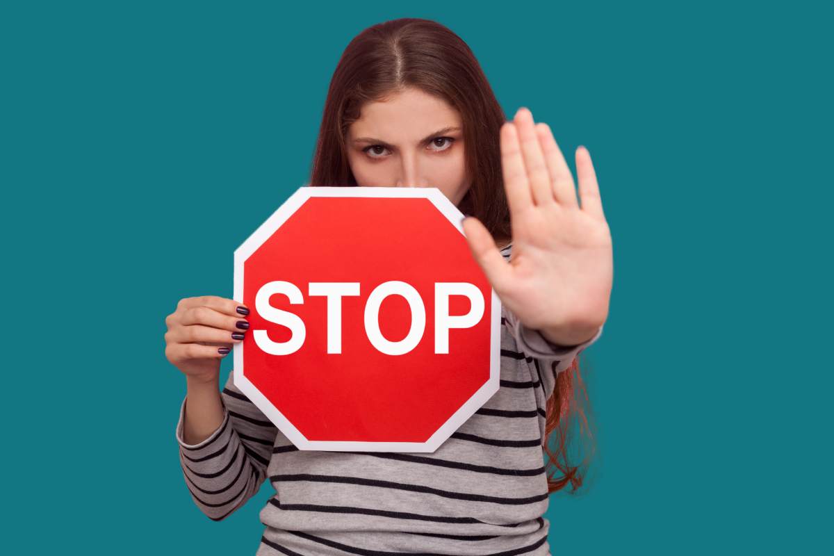 Woman holding a stop sign with her other hand up indicating 'stop' on a teal background.